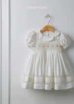 White baby girl dress with pintuck bodice and lace hem on hanger