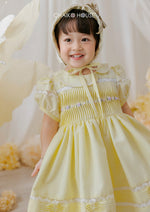 little girl smiling in lemon yellow occasion dress with puff sleeves and full skirt