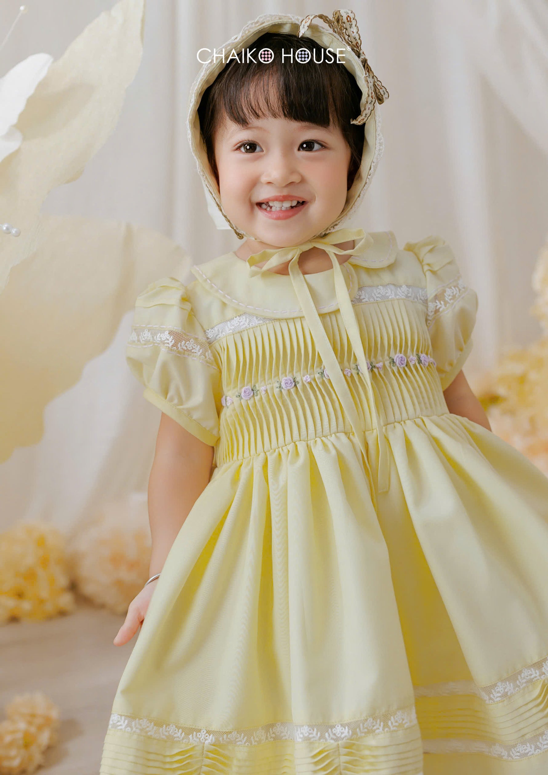 little girl smiling in lemon yellow occasion dress with puff sleeves and full skirt