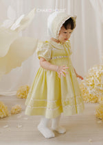 toddler in lemon yellow pintuck dress and matching bonnet in dreamy cream backdrop